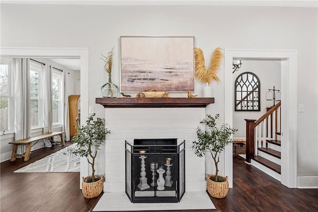 living room featuring a brick fireplace and dark wood-type flooring