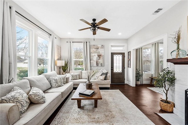 living room featuring ceiling fan, a fireplace, and dark hardwood / wood-style flooring