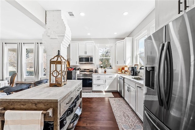 kitchen featuring dark wood-type flooring, sink, appliances with stainless steel finishes, white cabinets, and backsplash