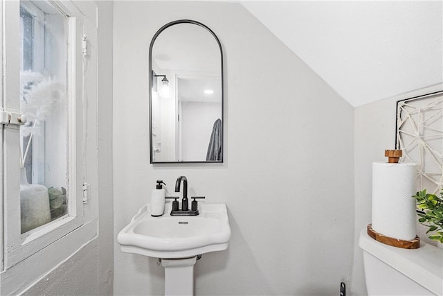 bathroom with lofted ceiling, toilet, and sink