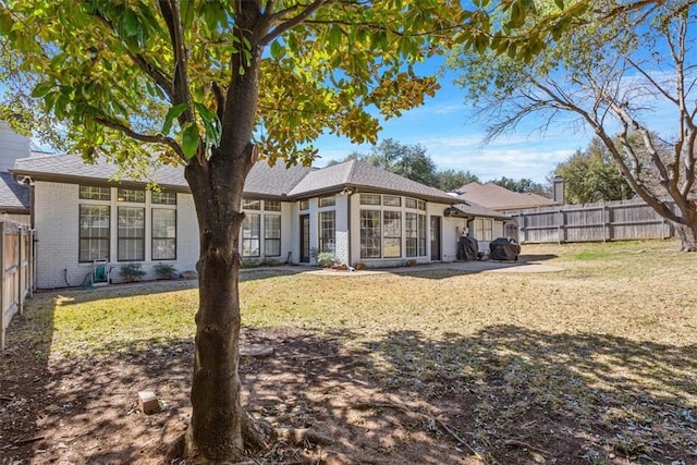 back of property with brick siding, a lawn, and a fenced backyard