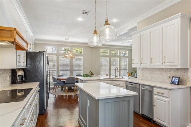 kitchen featuring appliances with stainless steel finishes, ornamental molding, white cabinetry, a sink, and a peninsula