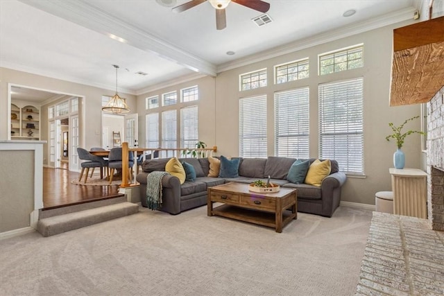 living area with carpet floors, a wealth of natural light, visible vents, and crown molding