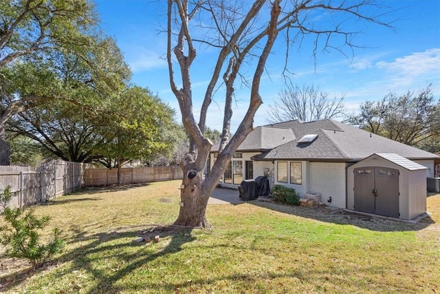 exterior space featuring an outbuilding, a yard, a storage unit, and a fenced backyard