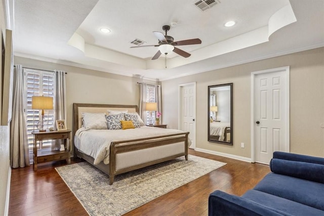 bedroom featuring baseboards, visible vents, a raised ceiling, and dark wood-type flooring