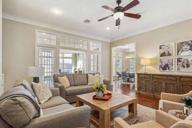 living room featuring crown molding, visible vents, ceiling fan, and wood finished floors