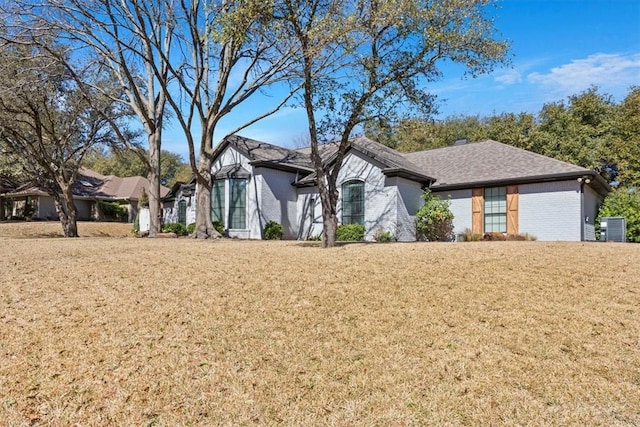 view of front of house featuring brick siding, a front lawn, and roof with shingles