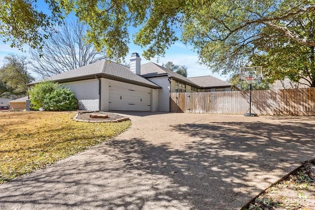 view of home's exterior featuring brick siding, fence, driveway, and an attached garage