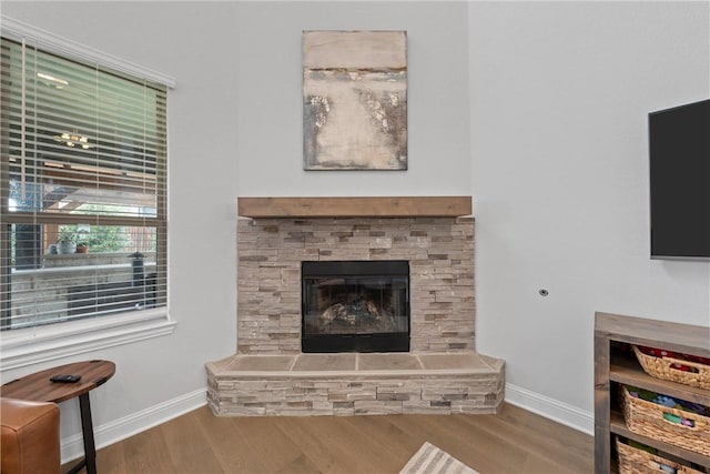 living room with hardwood / wood-style floors and a stone fireplace