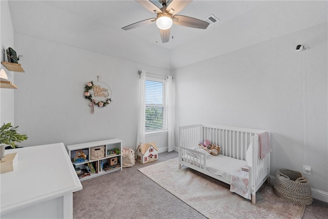 bedroom with ceiling fan, light colored carpet, and a nursery area