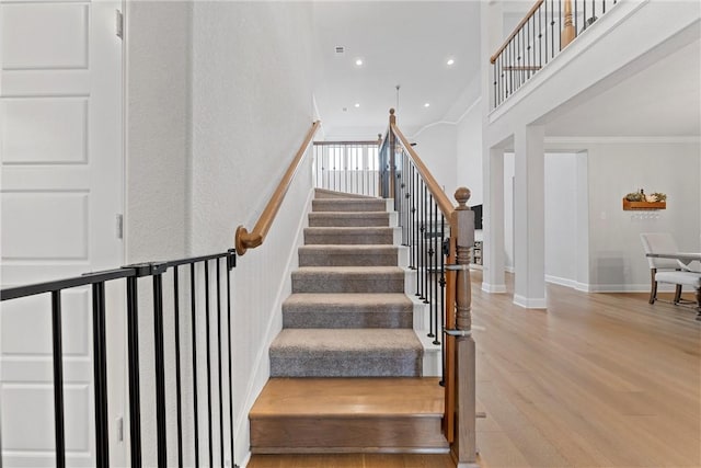 stairway with hardwood / wood-style floors and crown molding