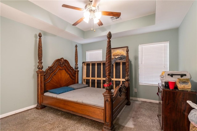 bedroom featuring multiple windows, carpet flooring, a raised ceiling, and ceiling fan