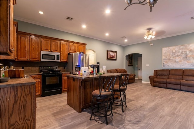 kitchen with a center island, stainless steel appliances, light hardwood / wood-style floors, a breakfast bar, and ornamental molding