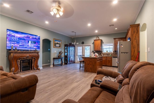 living room featuring ceiling fan with notable chandelier, light wood-type flooring, and ornamental molding