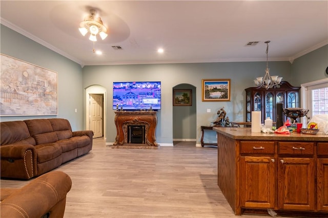 living room with ceiling fan with notable chandelier, crown molding, and light hardwood / wood-style flooring