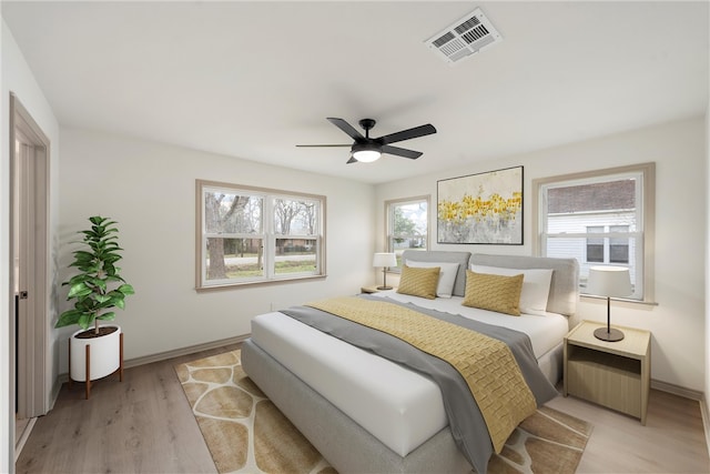 bedroom with baseboards, visible vents, light wood finished floors, and ceiling fan