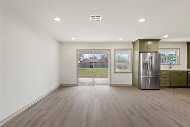 kitchen featuring light wood finished floors, visible vents, stainless steel fridge with ice dispenser, green cabinetry, and a sink