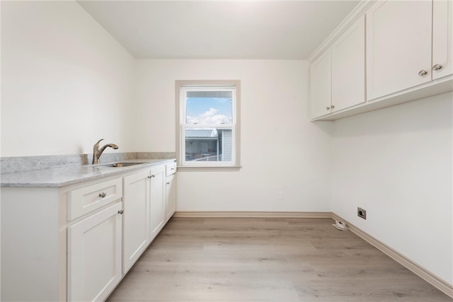 washroom featuring light wood-style flooring, a sink, cabinet space, baseboards, and hookup for an electric dryer