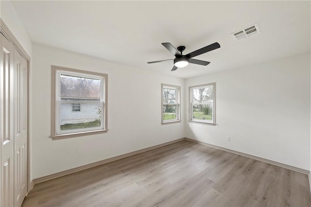 unfurnished bedroom featuring visible vents, a ceiling fan, a closet, light wood finished floors, and baseboards