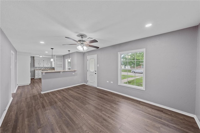 unfurnished living room with ceiling fan and dark wood-type flooring