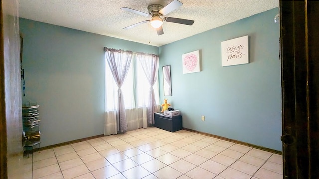 spare room featuring ceiling fan, light tile patterned floors, and a textured ceiling