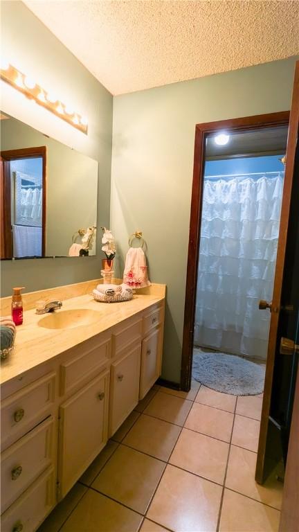 bathroom with tile patterned flooring, vanity, and a textured ceiling