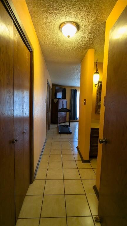 hall with light tile patterned floors and a textured ceiling