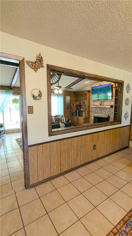 kitchen with wooden walls, ceiling fan, and a textured ceiling