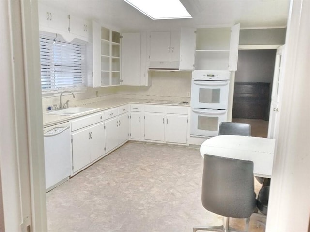 kitchen featuring sink, white cabinets, white appliances, and a skylight