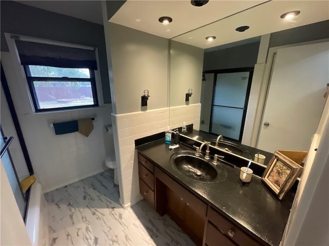 bathroom featuring vanity, toilet, and tile walls