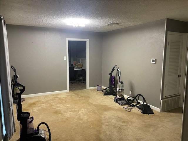 exercise area featuring light carpet and a textured ceiling