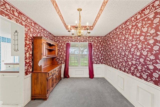 dining room with a raised ceiling, carpet, a textured ceiling, and a notable chandelier