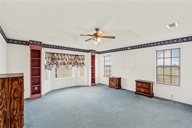 unfurnished room featuring ceiling fan, a tray ceiling, a textured ceiling, and carpet flooring