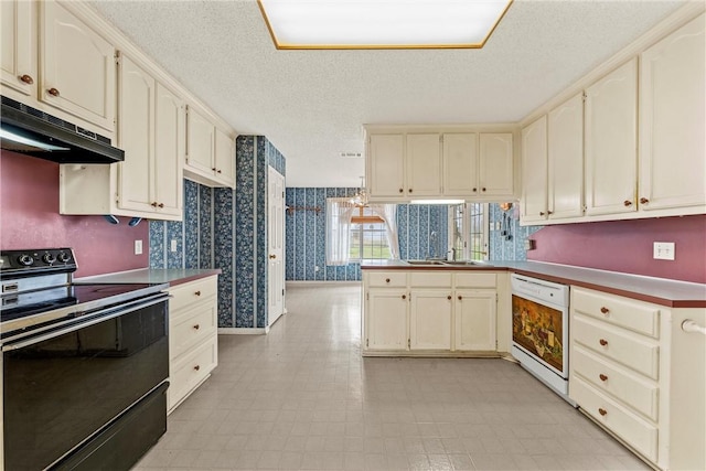 kitchen with dishwasher, electric range, kitchen peninsula, a textured ceiling, and cream cabinetry