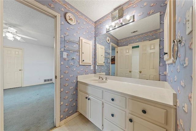 bathroom with ceiling fan, vanity, and a textured ceiling