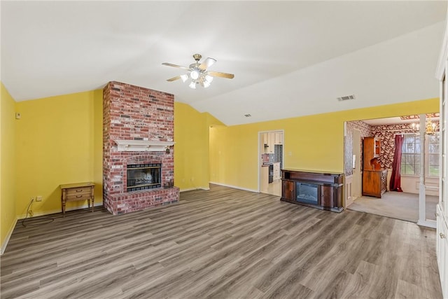 unfurnished living room featuring a brick fireplace, vaulted ceiling, wood-type flooring, and ceiling fan