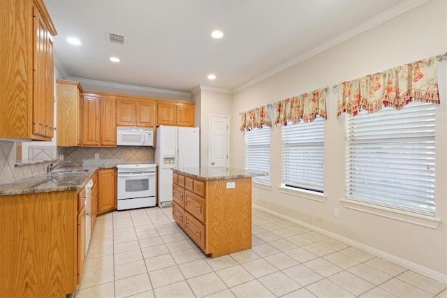 kitchen with backsplash, light stone counters, a kitchen island, and white appliances