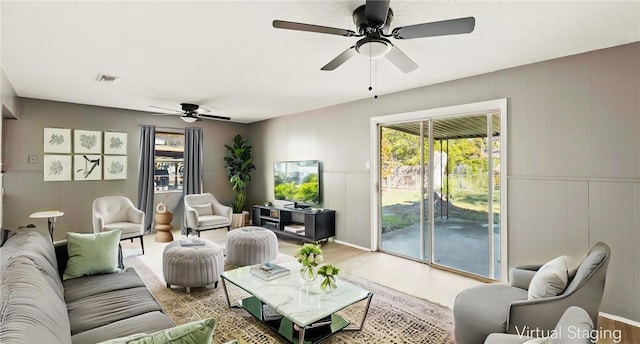 living room featuring ceiling fan, plenty of natural light, and light hardwood / wood-style floors