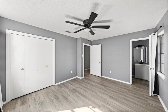 unfurnished bedroom featuring ceiling fan, light hardwood / wood-style flooring, a closet, and connected bathroom