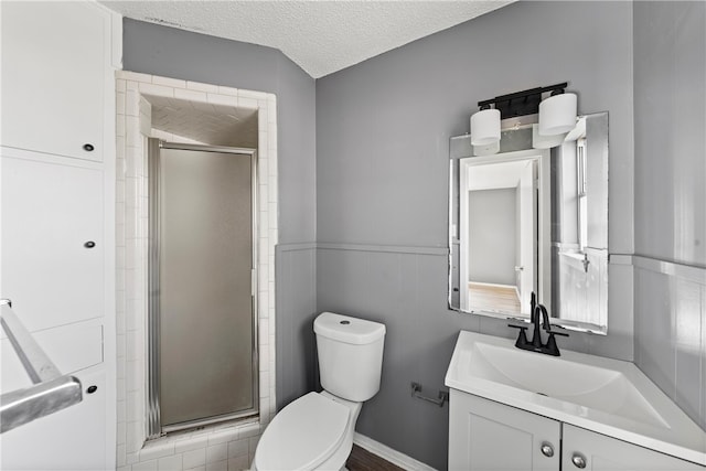 bathroom featuring toilet, an enclosed shower, vanity, and a textured ceiling