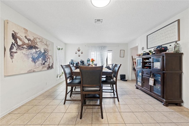 tiled dining space featuring a textured ceiling