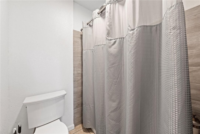 bathroom featuring tile patterned flooring, a shower with shower curtain, and toilet