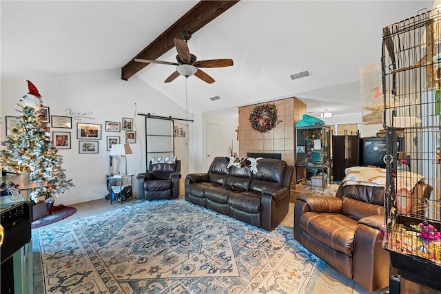 living room with a tile fireplace, lofted ceiling with beams, ceiling fan, a barn door, and light tile patterned flooring