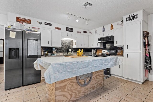 kitchen with stainless steel refrigerator with ice dispenser, extractor fan, light tile patterned floors, white cabinets, and a kitchen island