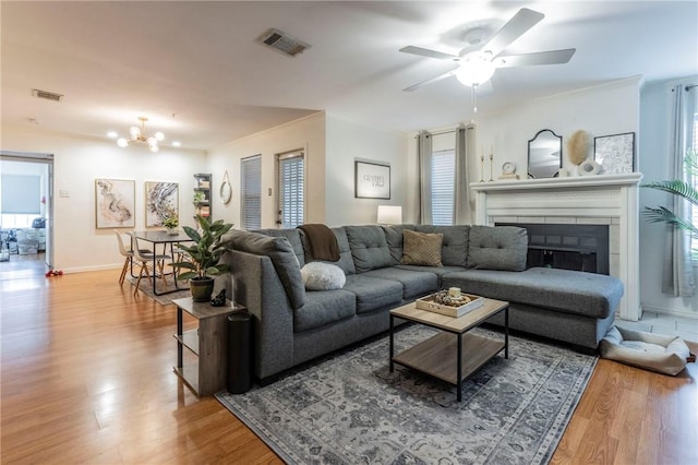 living area featuring plenty of natural light, a fireplace, visible vents, and wood finished floors