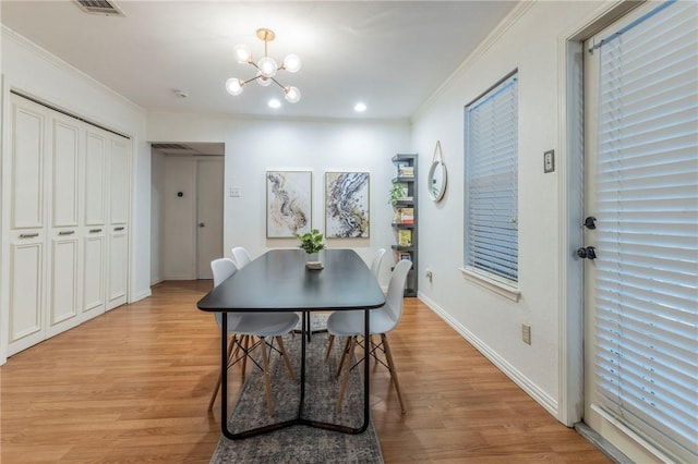 dining area featuring baseboards, light wood finished floors, crown molding, and an inviting chandelier