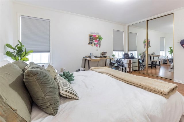 bedroom with a closet, crown molding, and wood finished floors