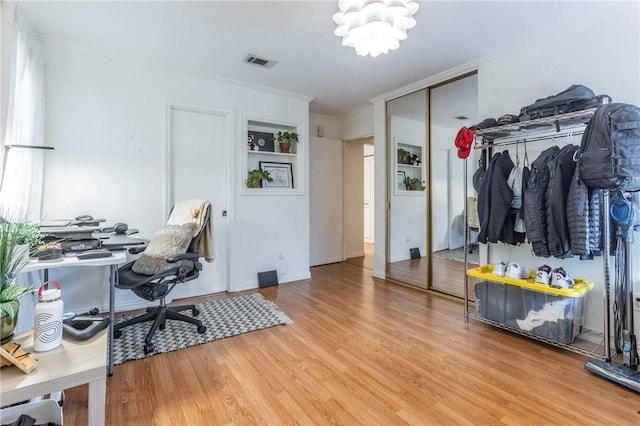 office area with light wood finished floors, visible vents, a chandelier, and ornamental molding