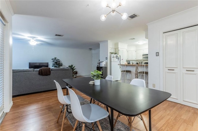 dining area featuring visible vents, crown molding, and light wood finished floors