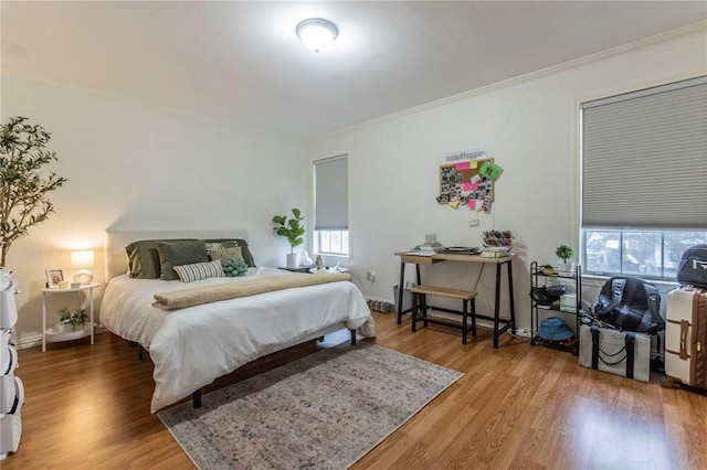 bedroom with crown molding, baseboards, and wood finished floors